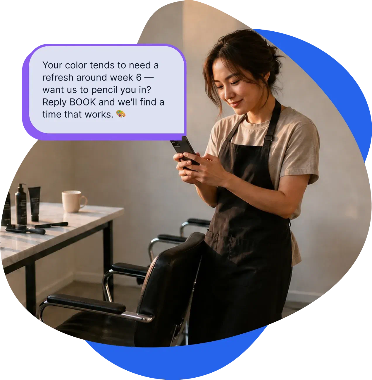 A stylist reading a client's reply on her phone in the salon